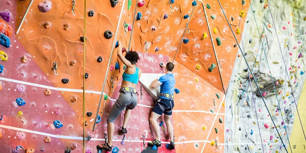 Deux personnes grimpent un mur coloré avec du ruban élastique personnalisable pour le sport et l'escalade.