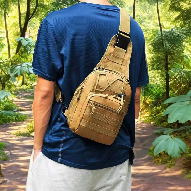 A person wearing a navy blue shirt carries a tan tactical sling backpack while standing in a wooded area.