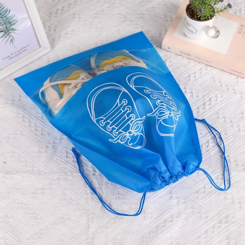 A blue reusable non-woven shoe storage bag with white line drawings of shoes is displayed on a white surface.
