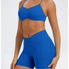 A model wearing a royal blue seamless high-waist yoga outfit consisting of a sports bra top and matching shorts.