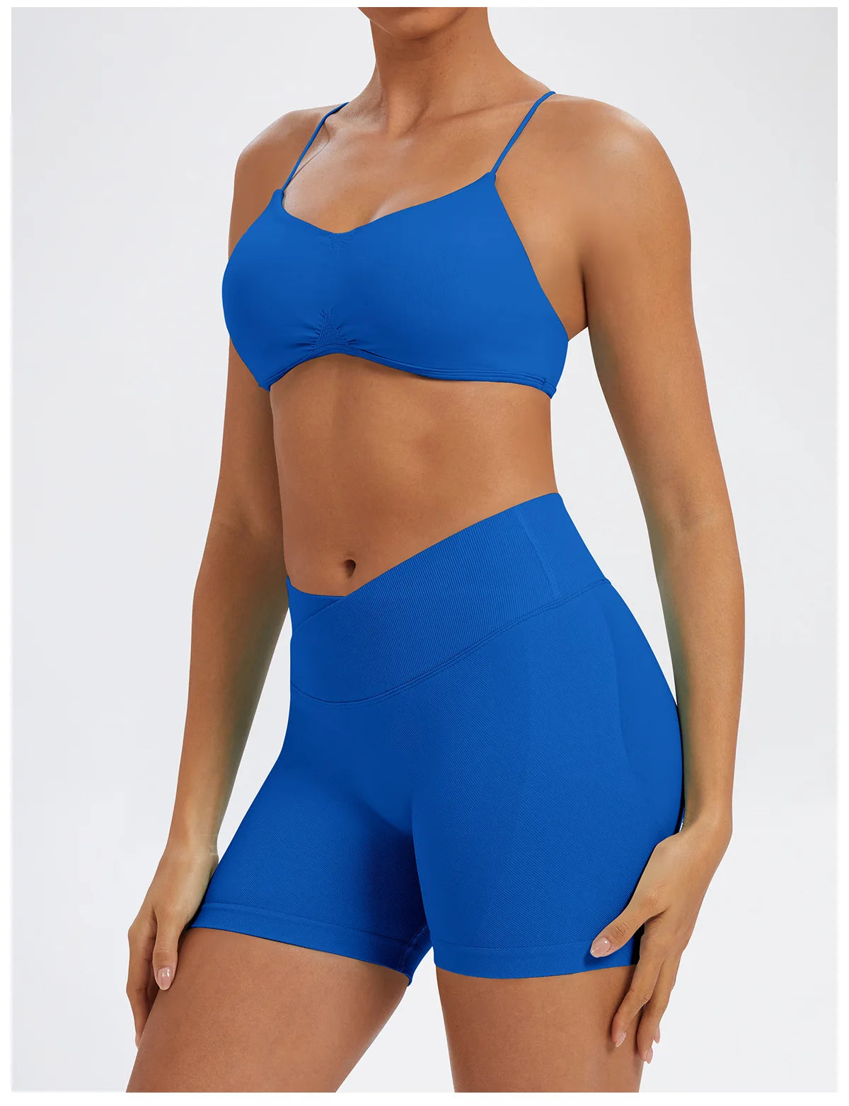 A model wearing a royal blue seamless high-waist yoga outfit consisting of a sports bra top and matching shorts.