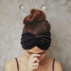 A person with reddish-brown hair wearing a black knotted headband, looking down.