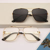 Gafas cuadradas con marco dorado y lentes oscuros, mostradas sobre un fondo claro.