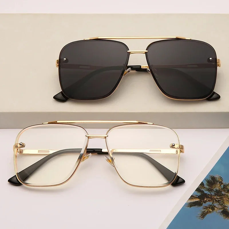 Gafas cuadradas con marco dorado y lentes oscuros, mostradas sobre un fondo claro.