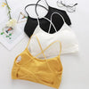 A collection of women's cross strap sports bras in black, white, and mustard yellow laid out on a white surface.