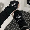 Eine Hand hält einen schwarzen fingerlose Armwärmer mit weißem Kreuzdesign.