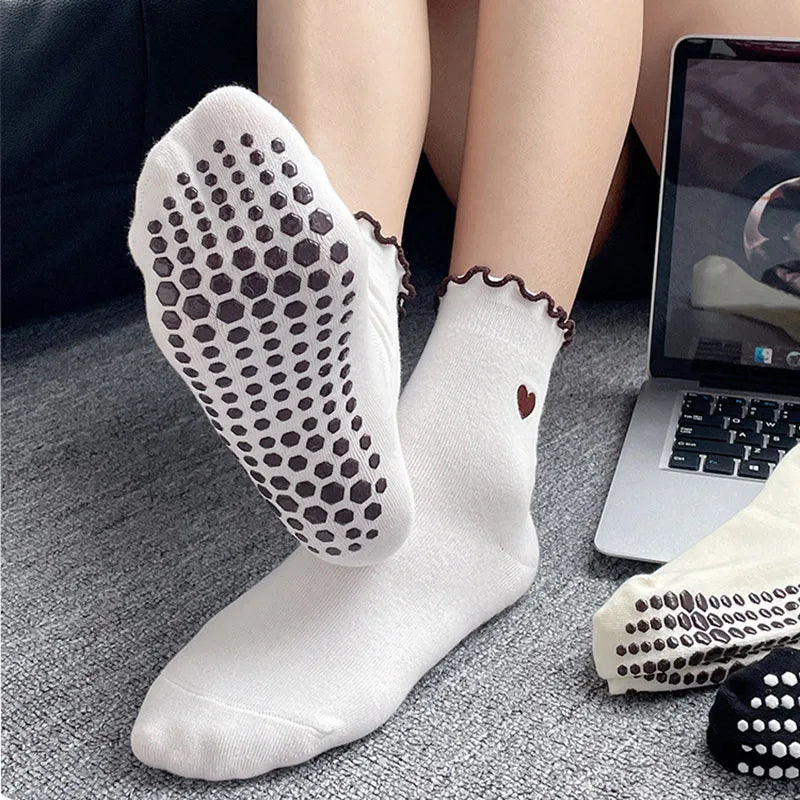White yoga socks with brown embroidery worn on a foot next to a laptop.
