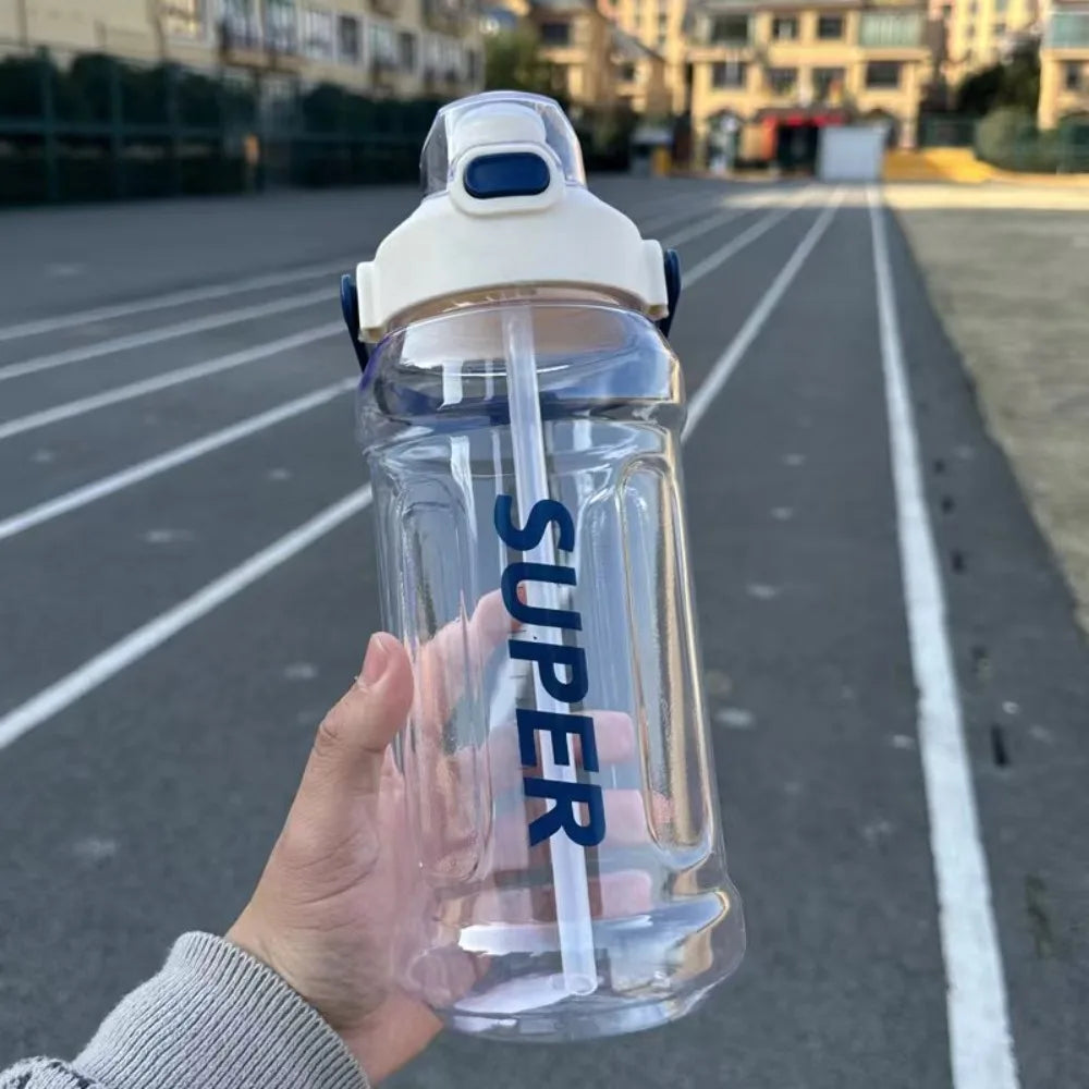 A hand holds a clear insulated sports water bottle with a white cap against an asphalt road background.