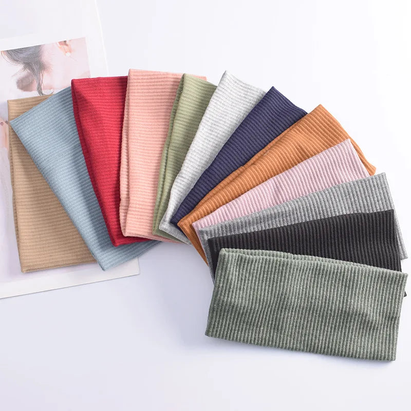 A collection of soft cotton knitted headbands in various shades of pink, red, green, and gray laid out on a white surface.