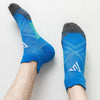 Ein Paar blaue Kompressions-Sportsocken, getragen am Fuß und Knöchel eines Menschen.