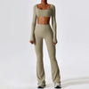 A woman models a beige women's performance tracksuit set consisting of a cropped top and matching full-length pants.