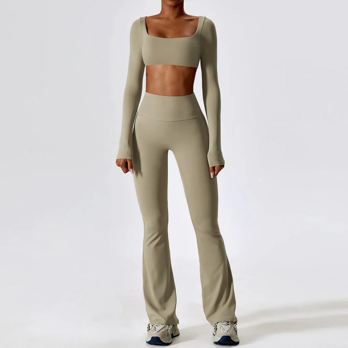 A woman models a beige women's performance tracksuit set consisting of a cropped top and matching full-length pants.