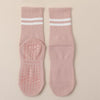 A pair of pink Pilates grip socks with white stripes and textured grip pads.