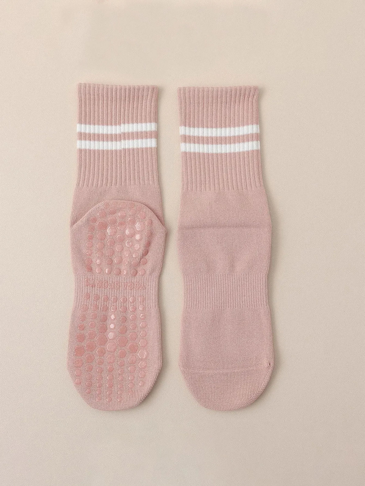 A pair of pink Pilates grip socks with white stripes and textured grip pads.