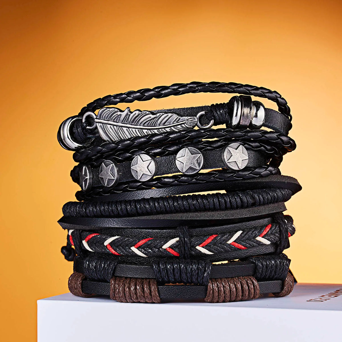 Stapel schwarzer Lederarmbänder mit verschiedenen Anhängern, darunter Feder und Sterne