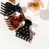 A set of three black and amber root lifting hairpin curling clamps shown against a white background.