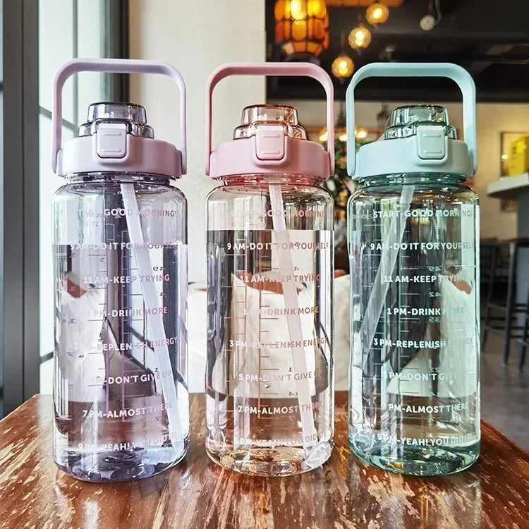 Three clear water bottles with pink and teal lids are displayed on a wooden surface.
