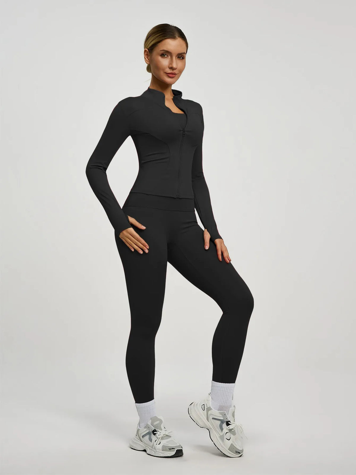 Eine Frau modelliert ein schwarzes Yoga-Sportset mit langärmeligem Oberteil und Leggings.