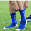 A close-up of a person's leg wearing blue athletic soccer socks with white soles on a green field.