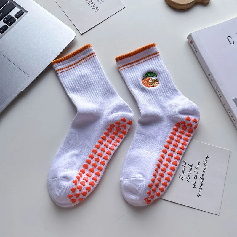 Paire de chaussettes de yoga blanches avec broderie orange et un petit motif de fruit