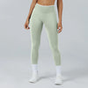A woman wearing light sage green high-waist yoga leggings and white socks.