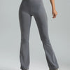 A model is wearing high-waisted grey bootcut yoga pants while standing.
