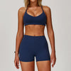 A woman models a navy blue 3-piece yoga sports set consisting of a crop top, sports bra, and shorts.