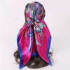 A vibrant pink satin square scarf with iridescent feather print tied in a bow
