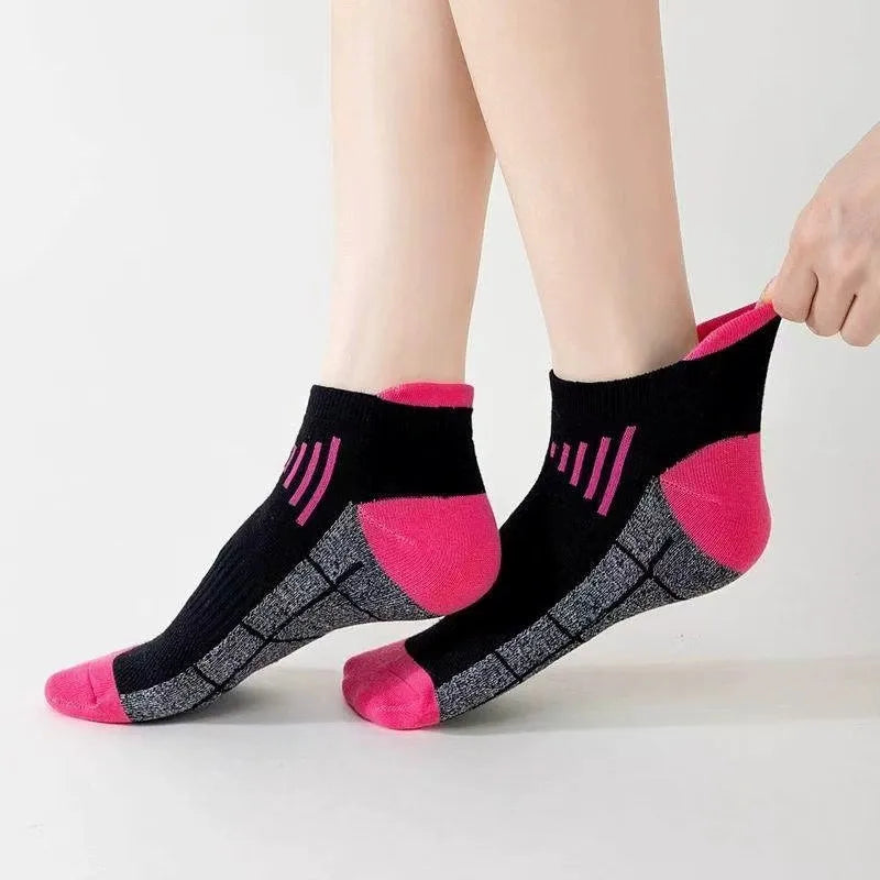 A pair of pink and black knit sports socks with a geometric pattern are shown on a person's foot.