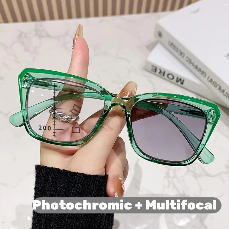 Eine Hand hält eine grüne photochromische multifokale Brille auf einer weißen Oberfläche.