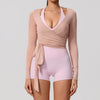 A woman wearing a light pink long sleeve top and matching shorts, featuring a wrap detail.