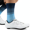 A close-up of a person's leg wearing blue and black patterned cycling socks and white athletic shoes.