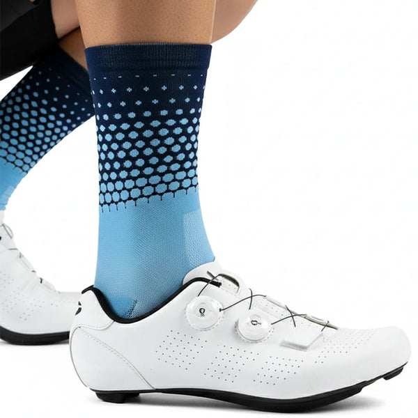 A close-up of a person's leg wearing blue and black patterned cycling socks and white athletic shoes.