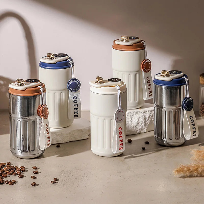 A collection of stainless steel and white insulated thermos bottles with wooden lids and fabric tags on a light surface.