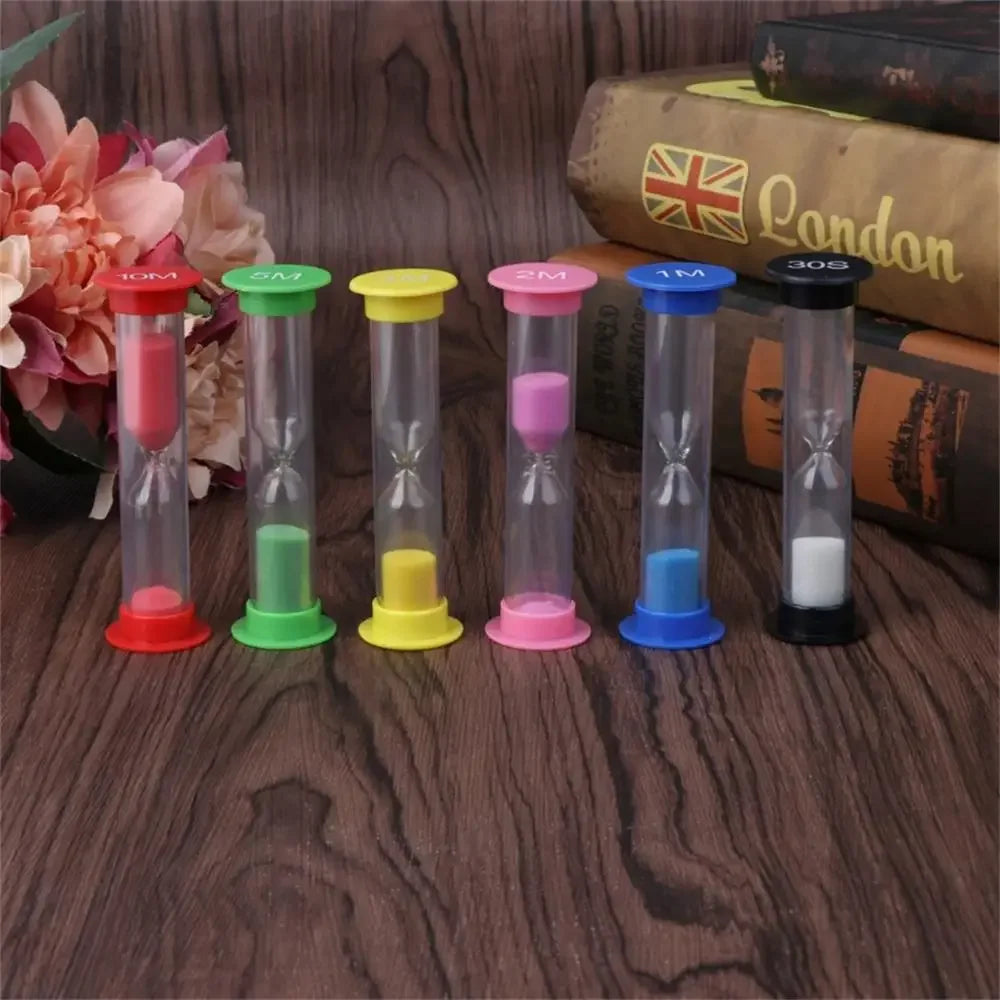 A set of six colorful sand timer hourglasses in various colors, displayed on a wooden surface next to a book.