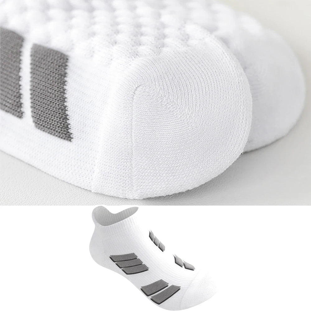 Une paire de chaussettes de sport blanches à coupe basse avec des rayures grises sur le pied et la cheville.