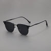 A pair of classic square metal frame sunglasses with dark lenses resting on a gray surface.