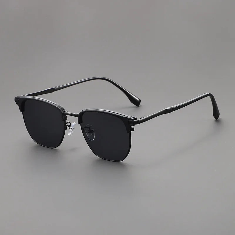 A pair of classic square metal frame sunglasses with dark lenses resting on a gray surface.