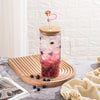 A glass tumbler filled with a pink beverage and topped with a silicone straw cover and a pink straw.