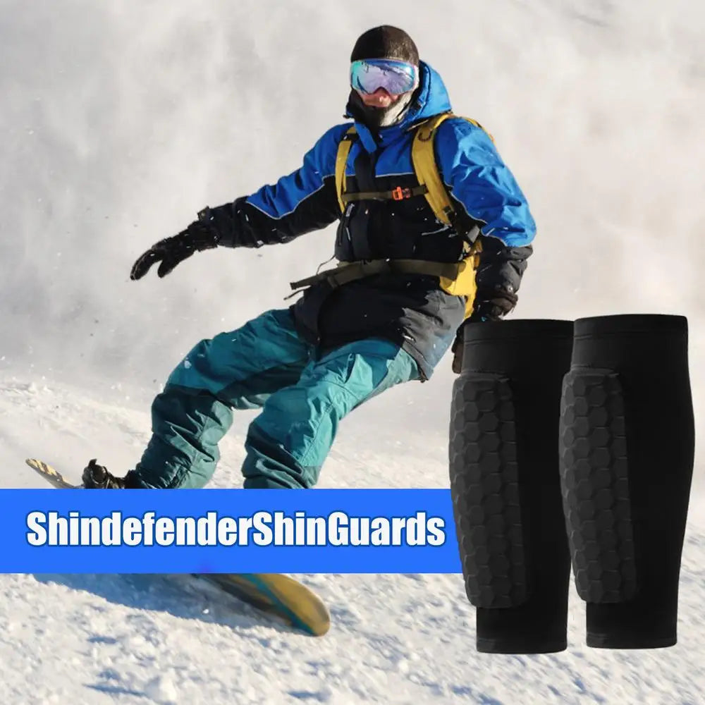 A person wearing blue and yellow gear is sliding on snow while holding black honeycomb leg guards.