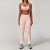 A woman models a three-piece pink yoga sports set consisting of a cropped top, leggings, and a sports bra.