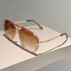 Vintage pilot gradient sunglasses with rose gold frames resting on a light surface.