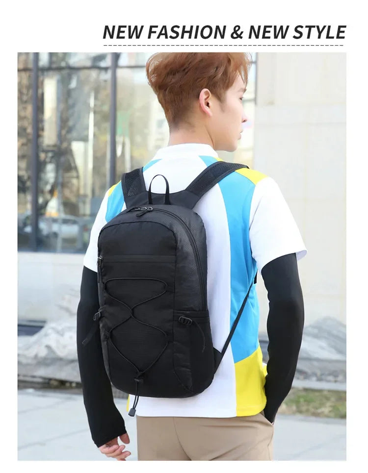 A person wearing a black large capacity waterproof outdoor hiking backpack over a white shirt and yellow accents.