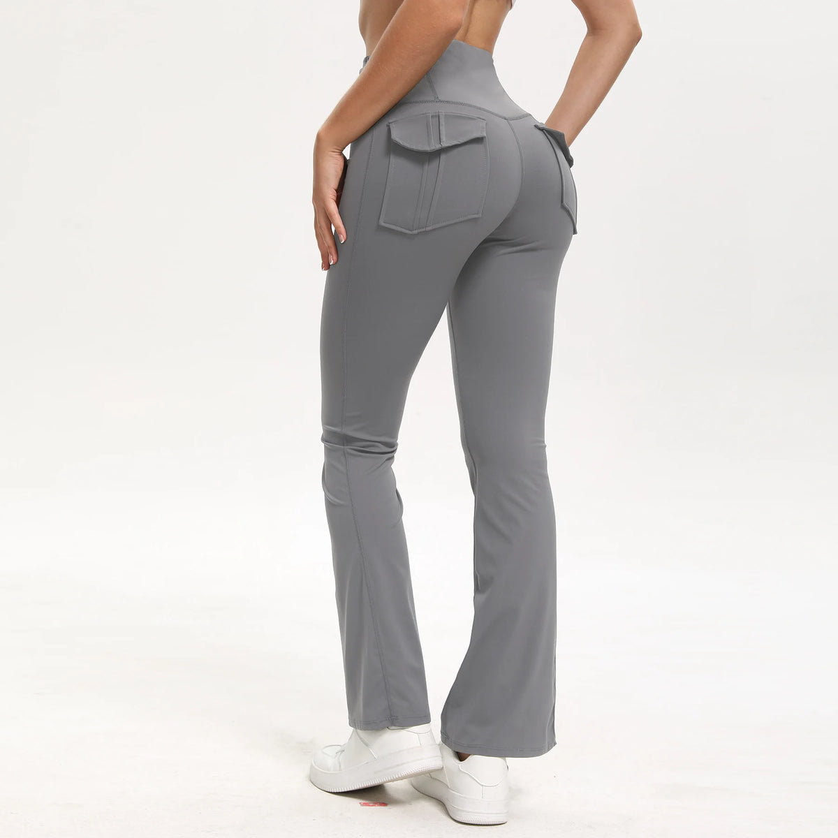 A model wearing gray high-waisted flared yoga leggings with a front pocket detail.