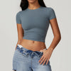 Una modelo vistiendo una camiseta de yoga y fitness azul claro y jeans de mezclilla.