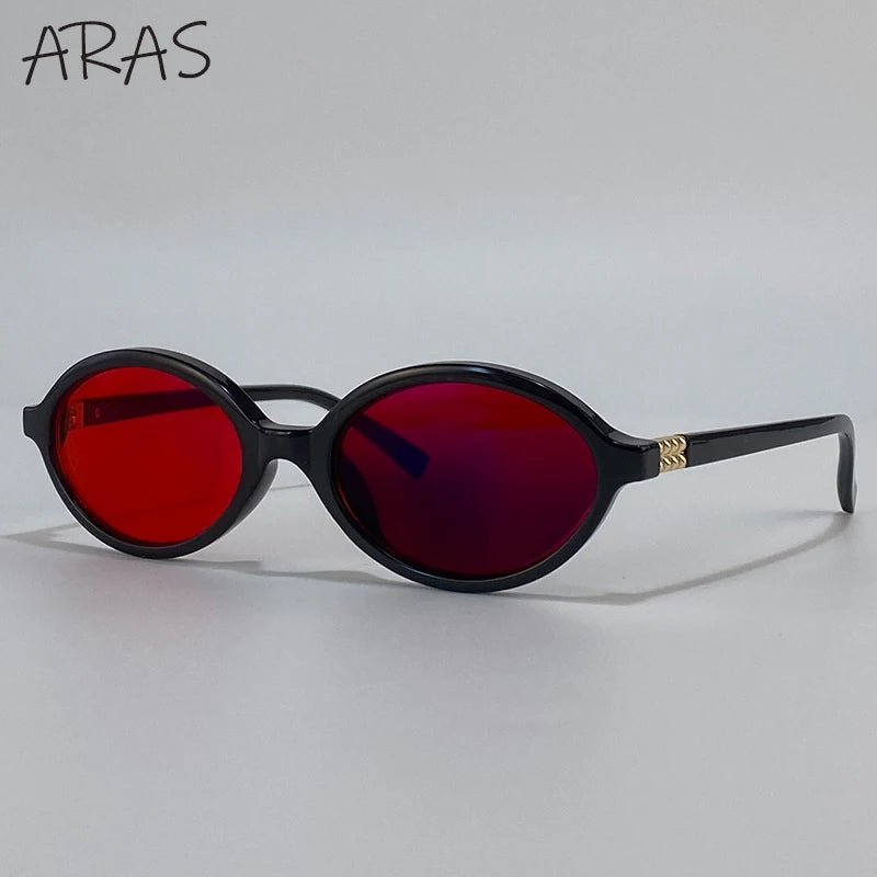 A pair of black anti-blue light glasses with red tinted lenses resting on a white surface.