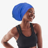 A woman wearing a blue silicone swimming cap and a black sports bra smiling.