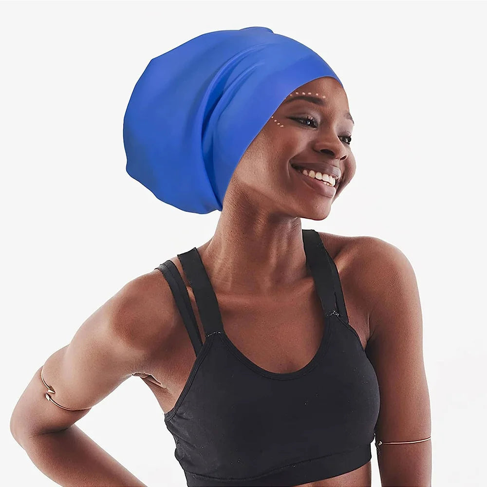 A woman wearing a blue silicone swimming cap and a black sports bra smiling.