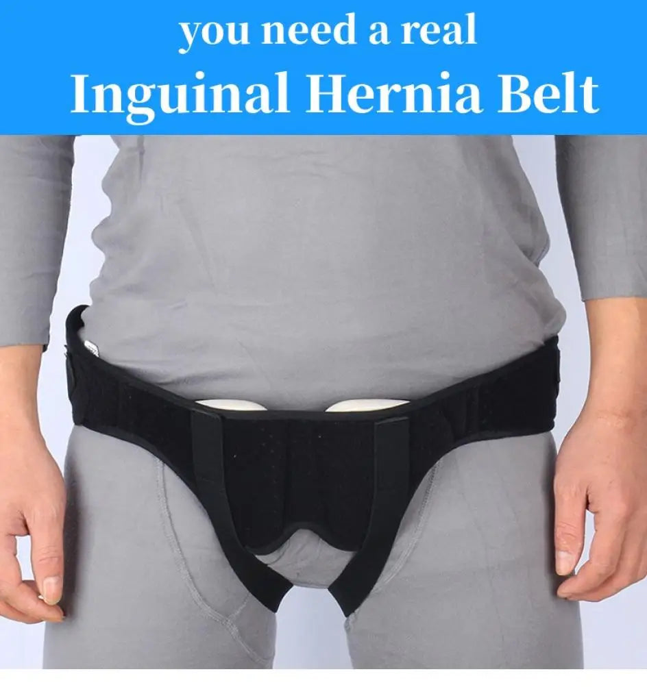A black inguinal hernia belt worn around the waist of a person wearing gray clothing.