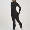 Eine Frau trägt ein schwarzes Langarm-Top und Leggings eines zwei-teiligen Yoga-Sportsets.